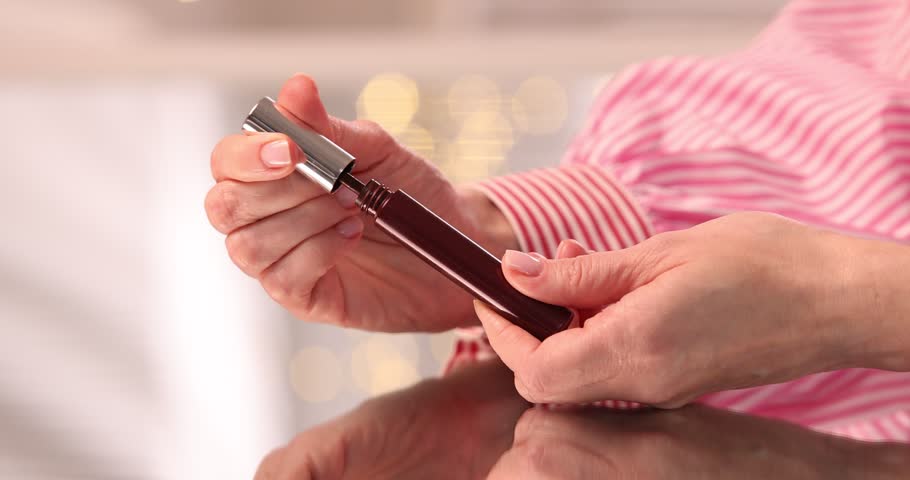 Woman with color mascara at table indoors, closeup