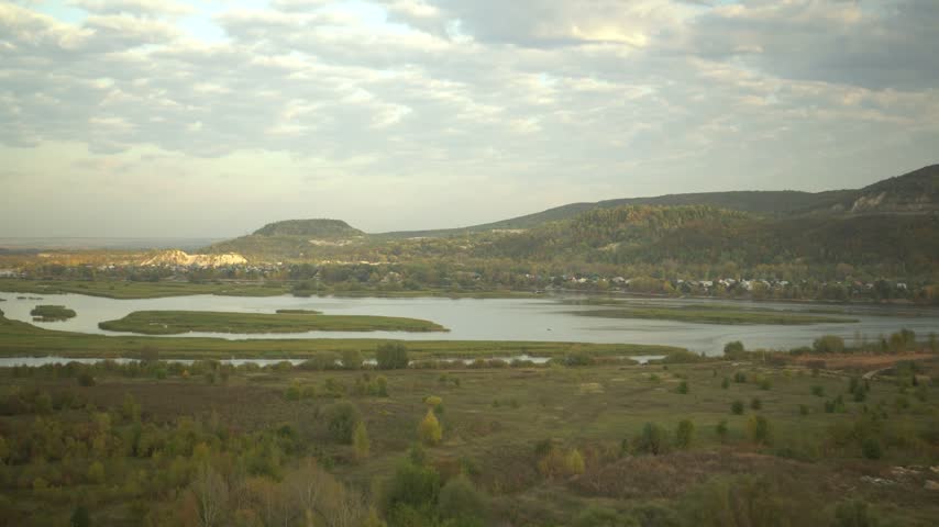 Panoramic Mountain Landscape With a River. A Wide Scenic View of Majestic Mountains and a Winding River Flowing Through the Valley.
