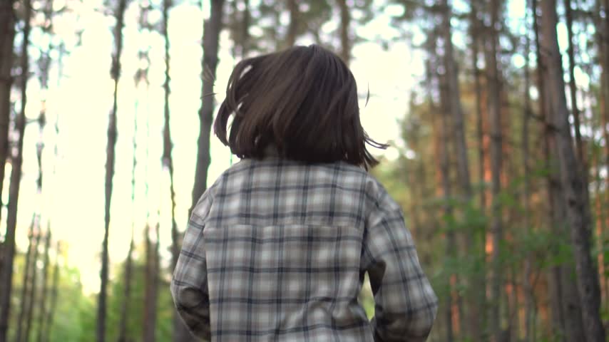 Woman Jogging in an Evergreen Forest. A Young Female Runner in Sunglasses Moves Along a Natural Woodland Path in Slow Motion, Rear View.