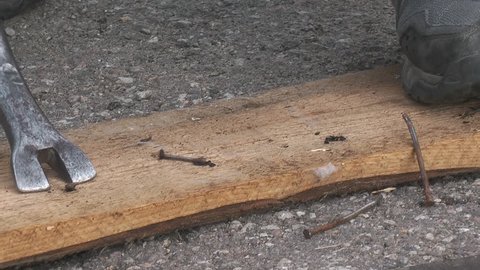 men pull off nails from plank with metal tool