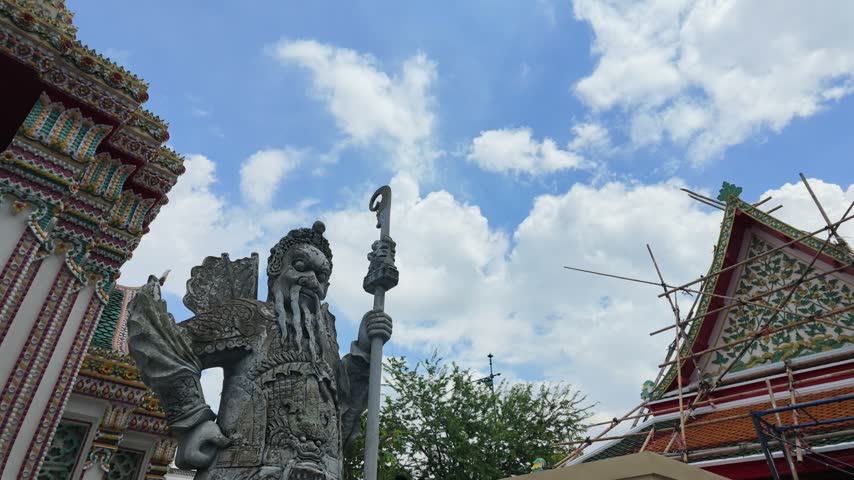 Low angle view of a Chinese stone warrior guardian statue against blue sky in Bangkok.