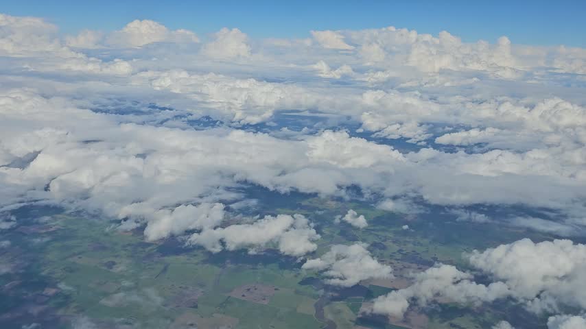 Aerial perspective of billowing cloud formations above a patchwork of rural fields and broad open countryside in Argentina.
