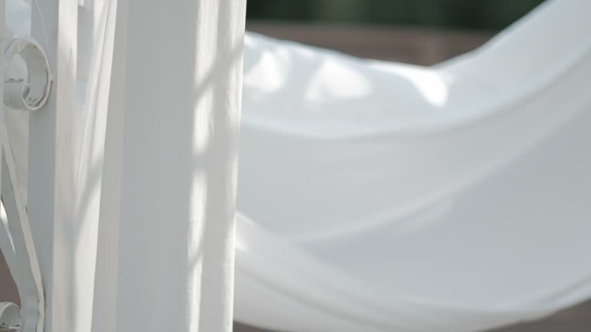 A close up of a white pillar next to draped fabric outdoors