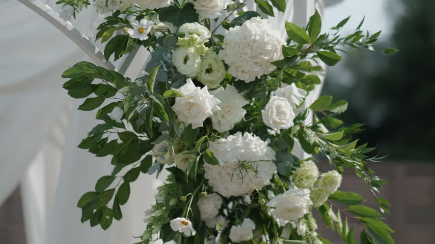 A beautiful arrangement of white roses and green foliage on a wedding arch