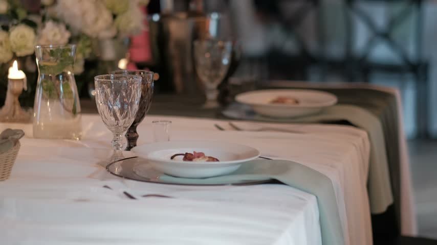 An elegant banquet table set for a wedding reception with fine china, crystal glasses, and appetizers
