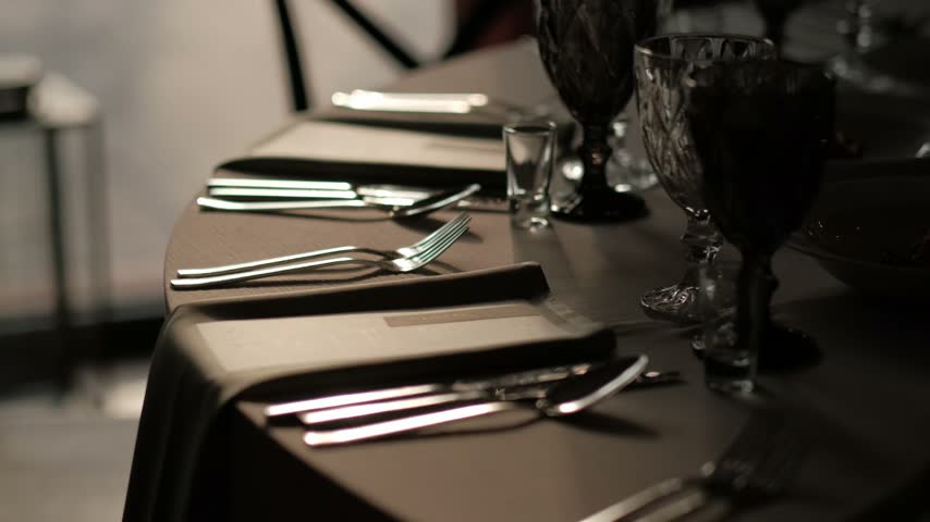Close up of elegant silverware and a folded napkin on a dark dining table