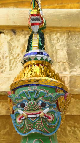 Tilt-down close-up of an ornate green Yaksha demon guardian statue at Bangkokâs Grand Palace.