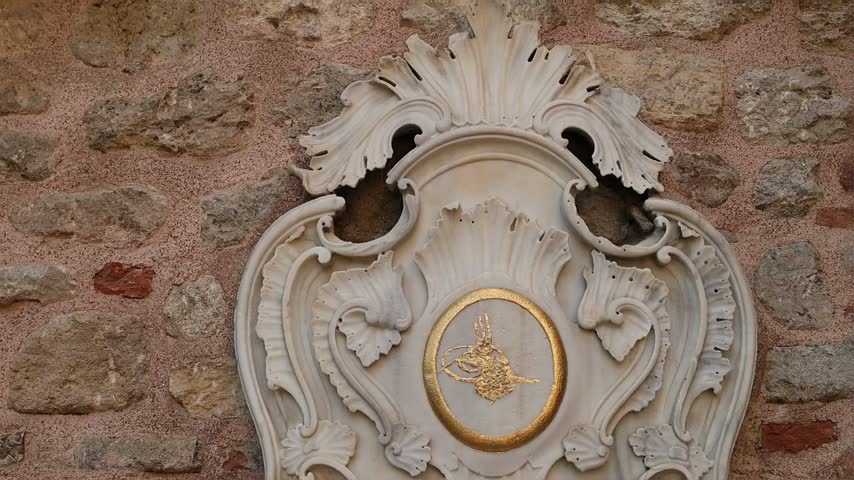 Ornate Ottoman marble fountain in Istanbul, Turkey, set into a historic brick and stone wall with decorative calligraphy and traditional architecture