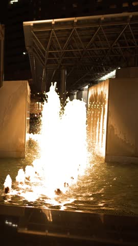 An illuminated modern water fountain sprays brightly at night in Kanazawa, Japan.