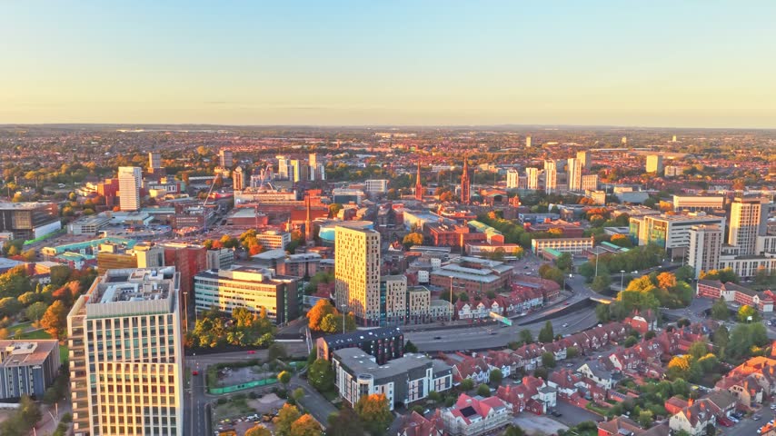 Coventry city centre towers, streets and rooftops in golden hour light in the West Midlands, England, aerial