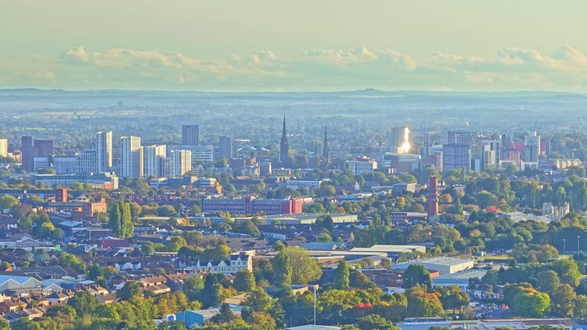 Coventry city centre skyline of towers and spires seen across northern suburbs and rail lines from near the arena in the West Midlands, England, drone slide parallax