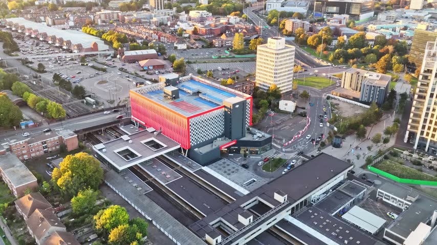 Coventry railway station platforms and multi storey car park with Friargate towers beyond in Coventry, West Midlands, England, aerial ascent