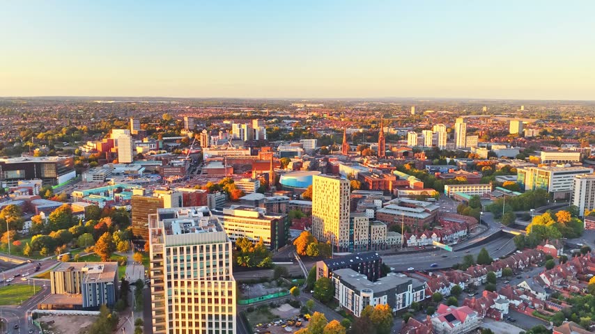 Coventry tower blocks, terraced streets and rooftops in golden hour light near the city centre in the West Midlands, England, drone lateral slide right