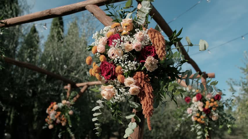 A beautiful floral wedding arch arrangement decorated with roses and autumn flowers outdoors