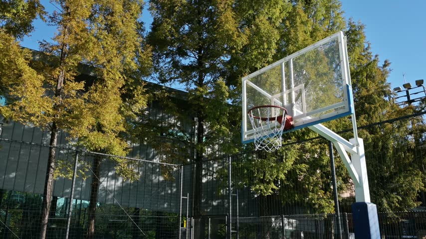 Empty outdoor basketball court in a park under clear blue sky in Korea.