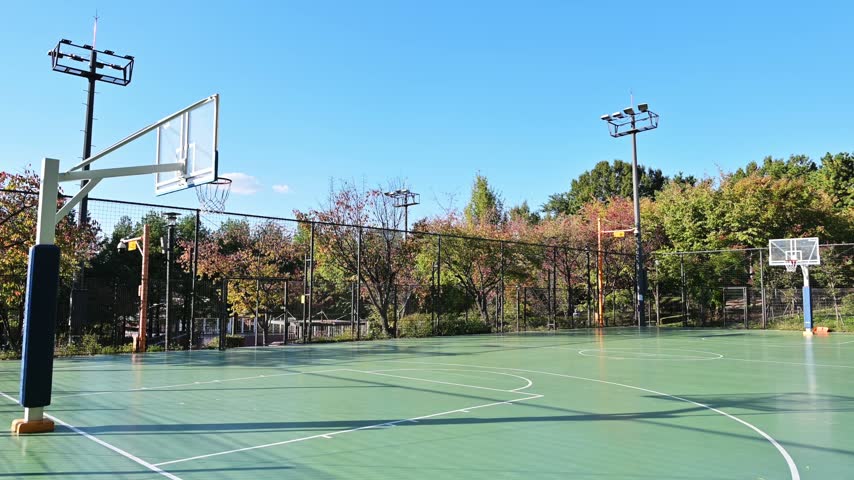 Empty outdoor basketball court in a park under clear blue sky in Korea.