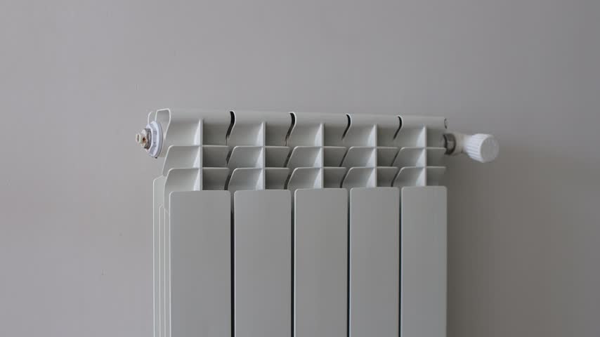 Person Dries and warms knitted gloves and a hat on a white radiator during winter.