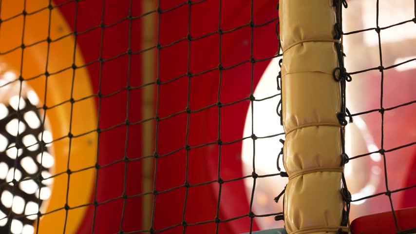 Bright sun light illuminating the interior of a colorful plastic playground through a safety net