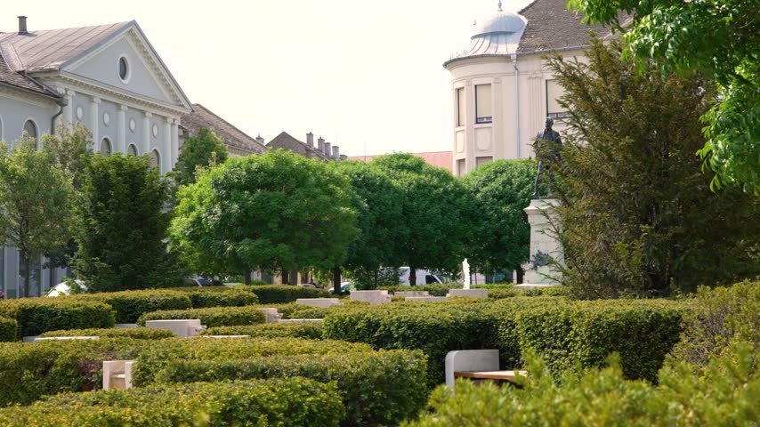 Green public park featuring a geometric hedge maze with benches in the city of Baja, Hungary