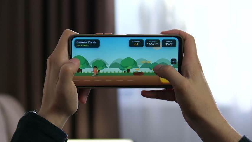 Person plays a colorful side-scrolling mobile game on smartphone, collecting items and completing a run, reflecting casual gaming, entertainment and interactive digital leisure.