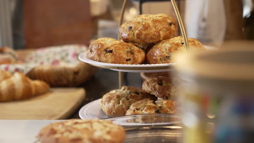 Golden blueberry scones displayed on a tiered serving tray in a cozy artisan bakery, Focus on texture, inviting rustic charm, and fresh baked goods.