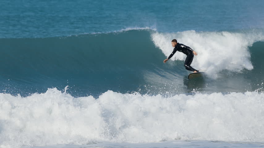 Surfer man riding on surfboard on ocean wave. Surfing slow motion