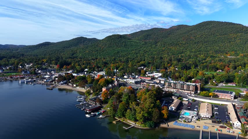 Aerial view of lakeside town with marina, forested hills, and waterfront buildings