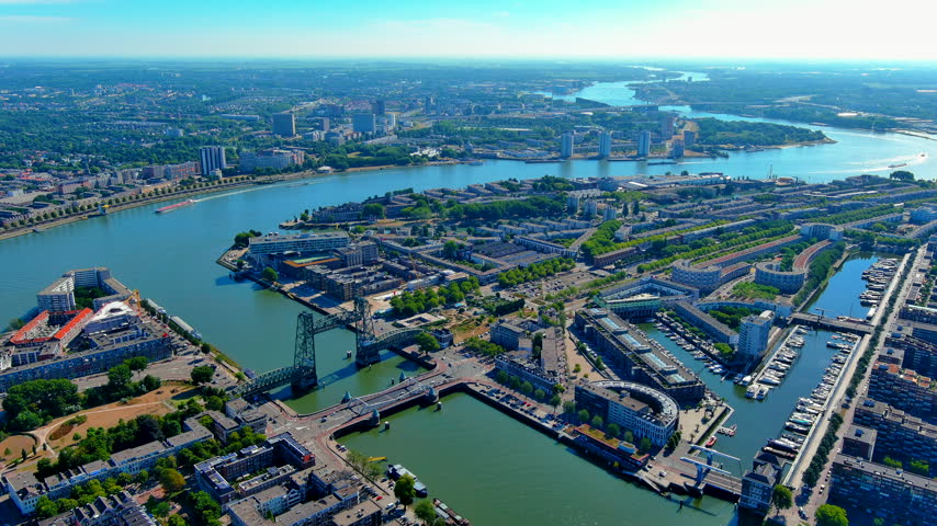 Drone view of Rotterdam, Netherlands, featuring the historic De Hef vertical lift bridge, nearby Koninginnebrug, marina berths, residential blocks and the broad Nieuwe Maas river.