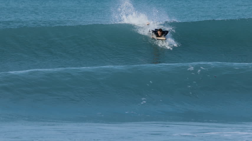 Surfer man on surfboard surfing on ocean wave. Slow motion