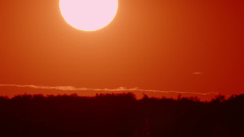 Sunset over the horizon with bright orange sky near the landscape