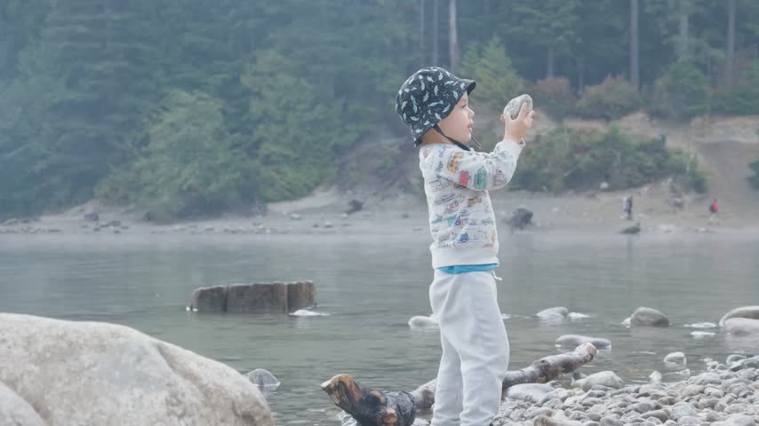 Little Boy Playing with Rocks by Alouette Lake in Golden Ears Park, British Columbia, Canada