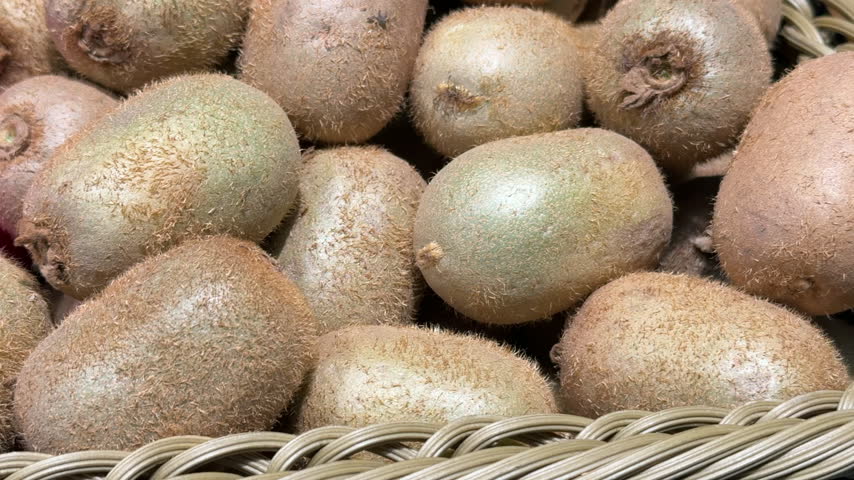 Fresh ripe organic kiwi fruits piled closely together in a rustic market display
