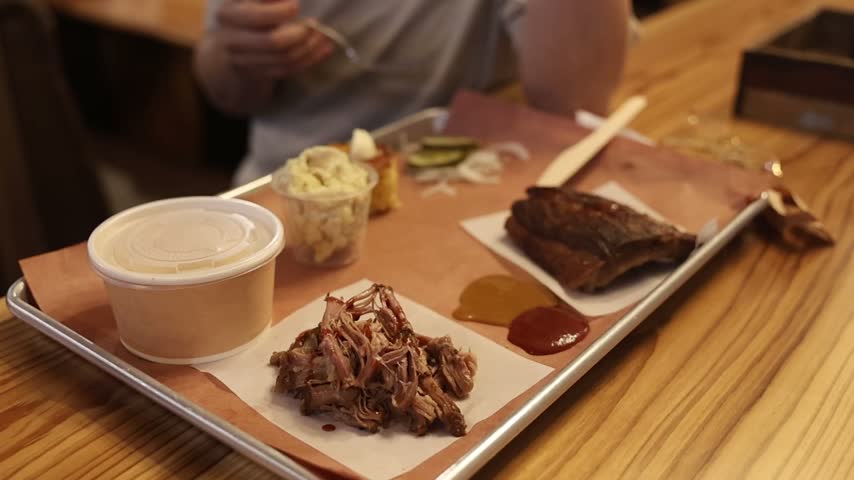 A plate full of delicious looking barbecued ribs and pulled pork with side dishes. 