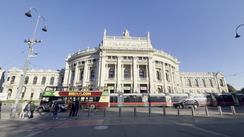 Historic building public plaza pedestrians street lamps tram vehicles in Vienne, Austria