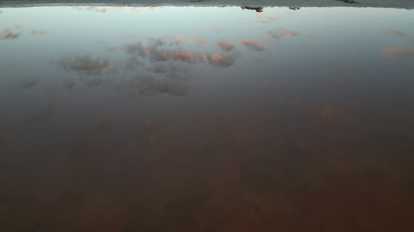 A view of clouds reflected on a calm lake surface.