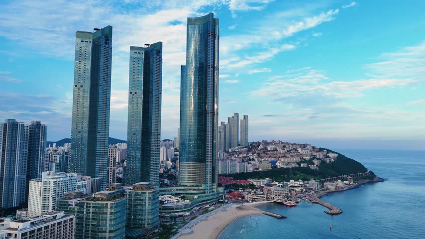 Aerial view of haeundae beach showing modern skyscrapers along the coastline against a scenic morning sky in busan, south korea