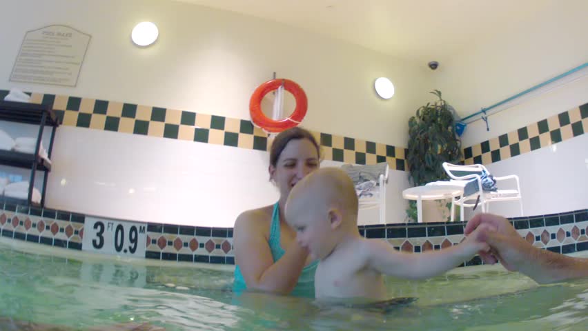 A family with a toddler swimming at the swimming pool underwater shot