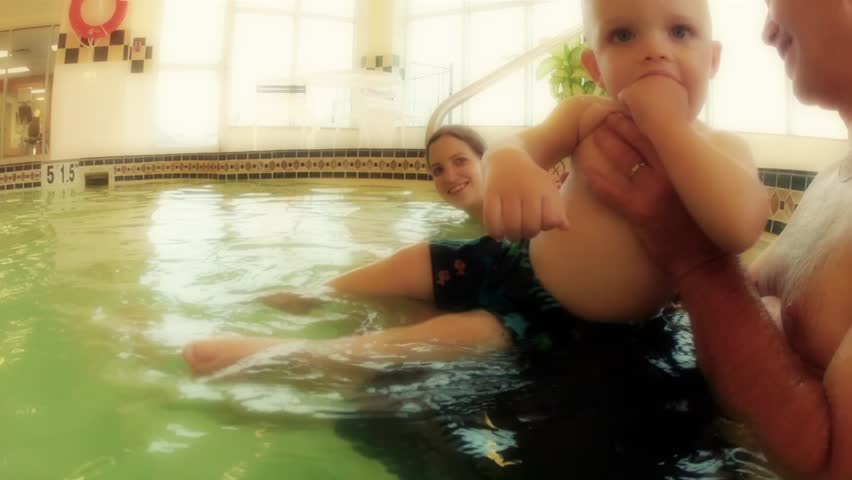 A family with a toddler swimming at the swimming pool underwater shot