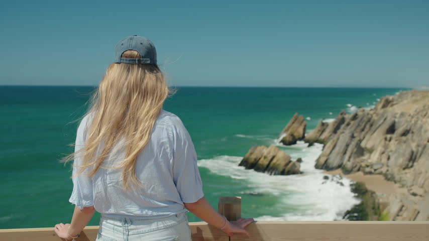 A woman in a white shirt and cap overlooks Portugal