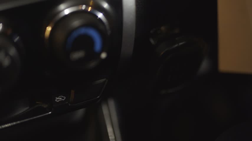 Close up of hand reaching for radio on car dashboard