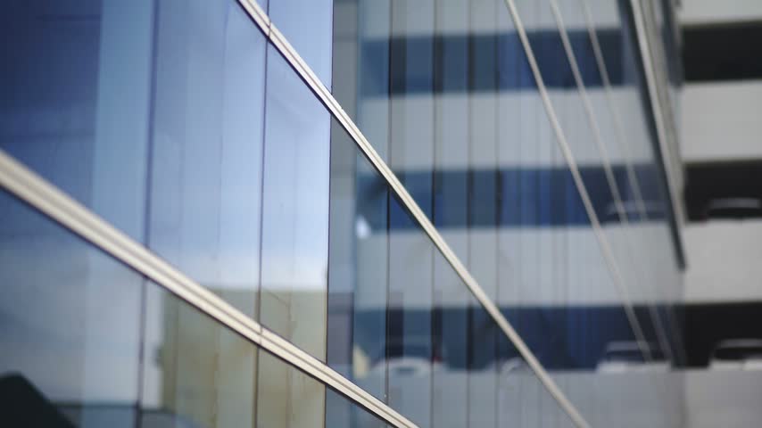 Looking up at glass skyscraper and office tower with blue sky