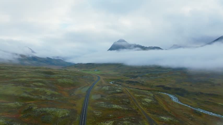 Low clouds veil dark mountain summits above a remote Akureyri valley road