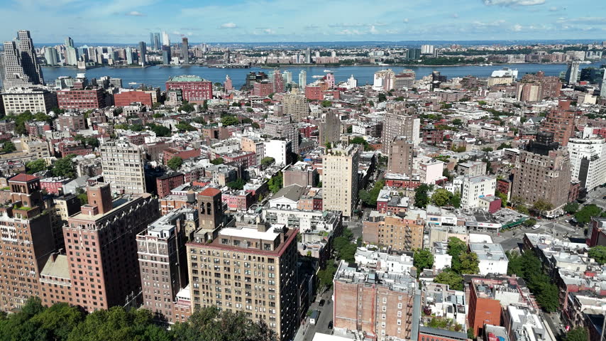 Aerial tilting up over Greenwich Village apartment blocks and leafy streets to reveal the Hudson River and New Jersey waterfront, Manhattan, New York City, USA.