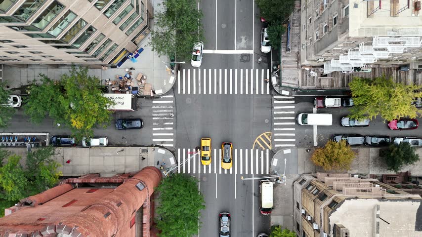 Top down aerial rising over a busy Upper East Side intersection with taxis, crosswalks and tree lined sidewalks, Manhattan, New York City, USA.
