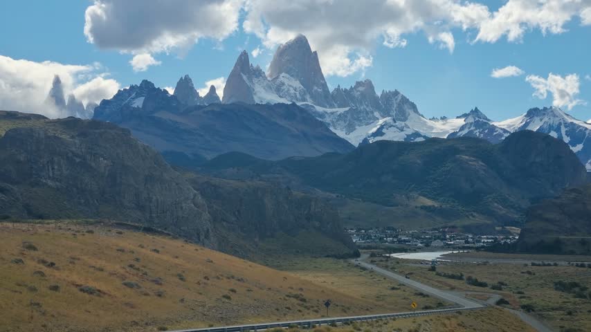 Panoramic view of the iconic Fitz Roy massif towering over El Chaltén, Argentina, with dramatic Andean peaks rising above the vast Patagonian wilderness. A breathtaking landscape for outdoor tourism