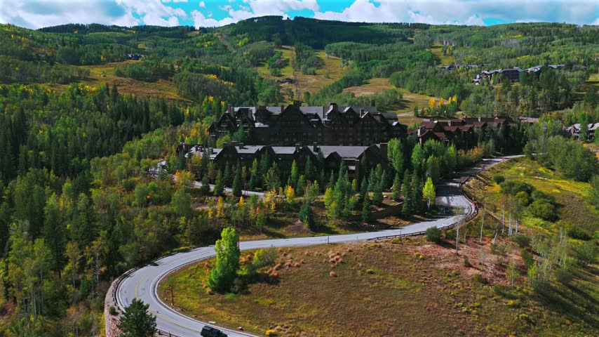Aerial drone view of Beaver Creek Ski Resort ski trails lift sunny blue sky morning Fall Autumn Bachelor Gulch Vail Avon Colorado landscape Ritz Carton ski lodge buildings cars road forward pan up