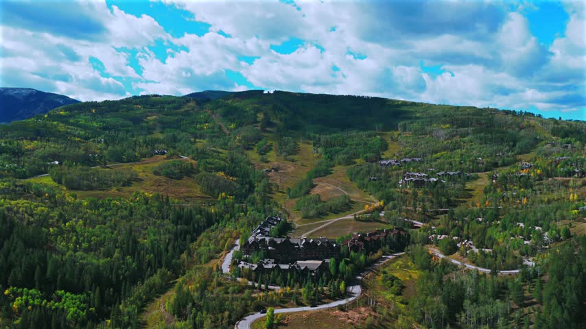 Aerial drone view of Beaver Creek Ski Resort ski trails sunny blue sky morning Fall Autumn Bachelor Gulch Vail Avon Colorado landscape Ritz Carton ski lodge buildings cars windy road circle right