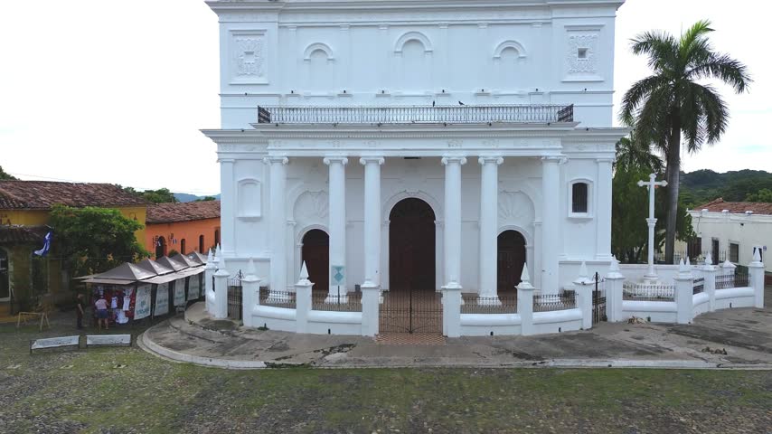 Aerial tilt up reveal shot from Santa Lucia Church facade to colonial town of Suchitoto