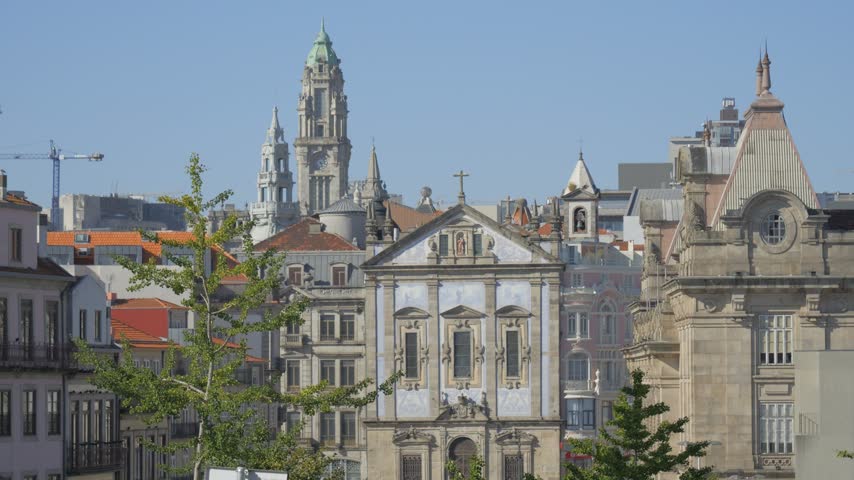 Igreja de Santo António dos Congregados stands among ornate buildings and tiled rooftops in Porto, with a tall bell tower rising behind it.