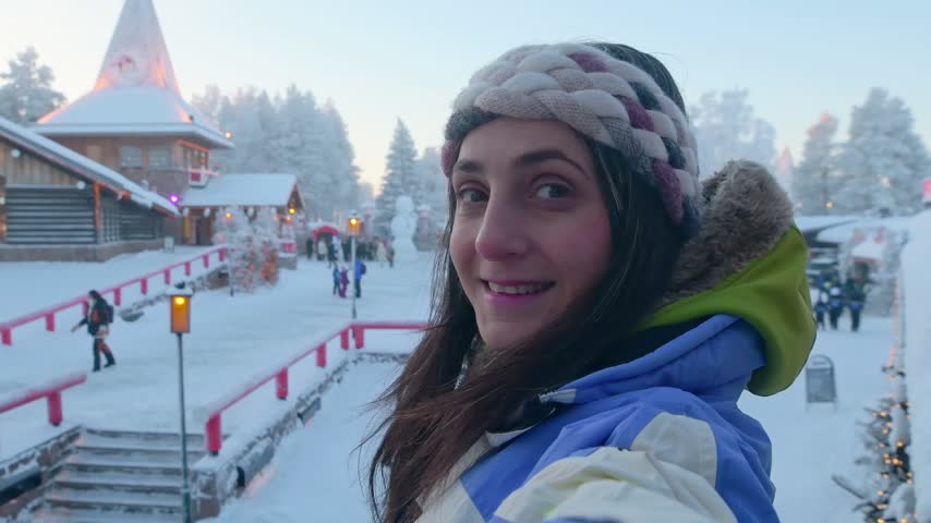 Happy tourist woman waving to camera inside Santa Claus Village Rovaniemi Lapland Finland winter vacation Christmas destination smiling traveler blogger